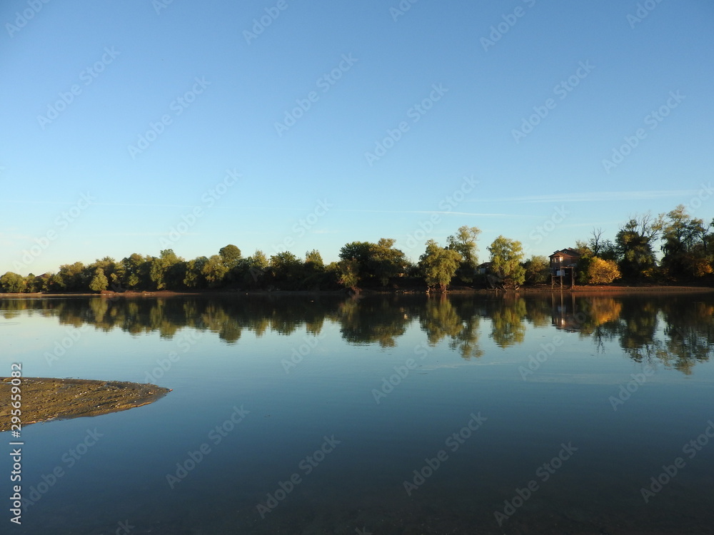 Fototapeta premium Mirror surface of water in the river in the early autumn evening