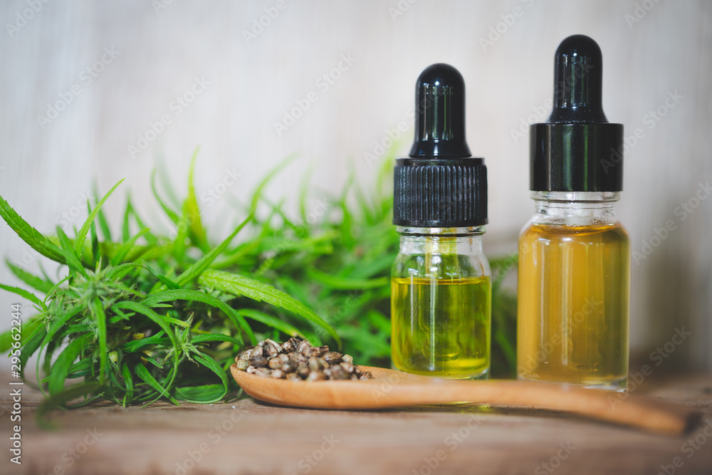 CBD oil hemp products, Medicinal cannabis with extract oil in a bottle on a wooden table. Medical cannabis concept CBD oil hemp products, Medicinal cannabis with extract oil in a bottle on a wooden table. Medical cannabis concept