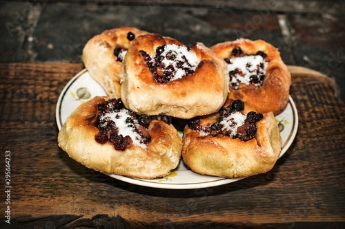 Homemade open pies with berry filling in a plate on a wooden textured surface