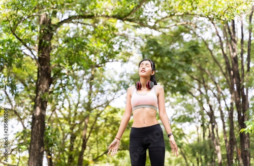 Healthy woman are inhaling fresh air during exercise in a happy and relaxing mood at the park with green leaves blur bokeh background and sunlight in sport and healthy concept with copy space.