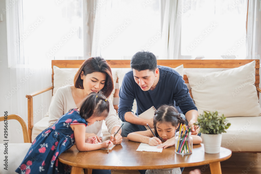 Asian family with cute daughters painting art in living room at home Asian family with cute daughters painting art in living room at home