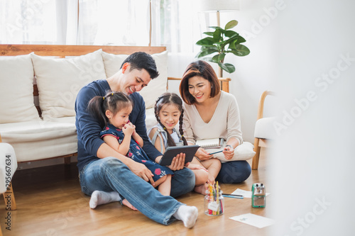 Happy Asian family using tablet, laptop for playing game watching movies, relaxing at home for lifestyle concept photo