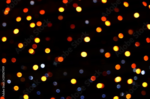 Many soft orange, yellow, red and blue blurry bokeh light on dark tone background in Christmas and New Year festival day, can use for background