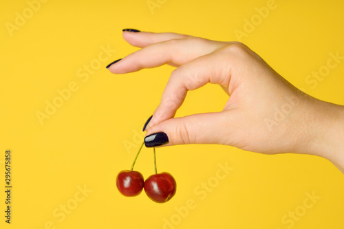 girl holds sweet cherry in hand