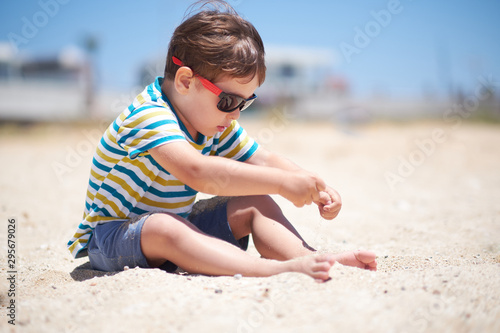 holiday, little boy three years old fun digging in the sand at the beach