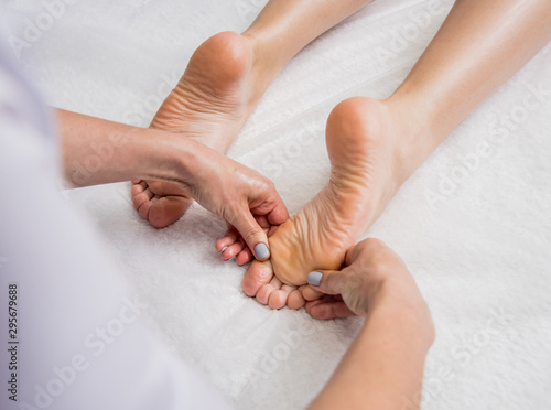 Beautiful young woman enjoying foot massage in spa salon. Cosmetology