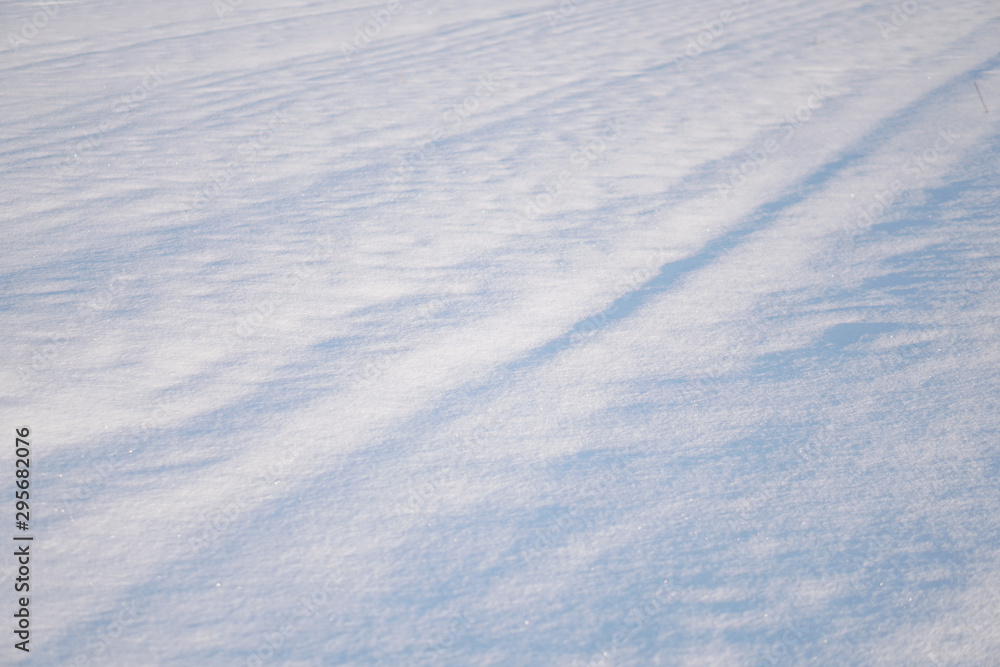 Snow-white snow and the earth sheltered by it. Countryside and snowfall. Winter dunes and mountains of snowflakes. Stock background.