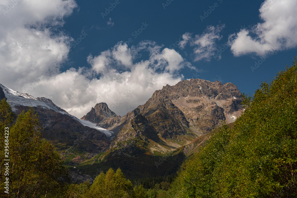 Mountain landscape with a blue sky with clouds surrounded by green trees, Dombay Caucasus