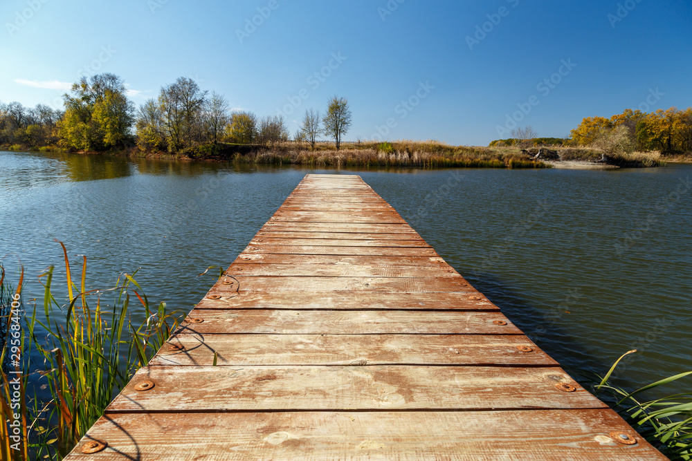 Naklejka premium Old pier on the river on a sunny autumn day.