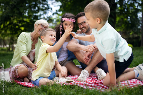 Happy male and female playing and enjoying picnic with children outside © NDABCREATIVITY