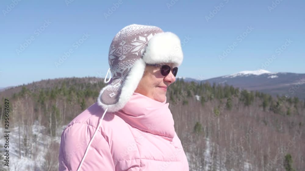 Grandmother looks around on a beautiful New Year and winter day. Joyful aged woman looks around and smiles at nature