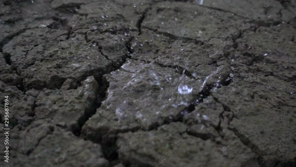 Raining on cracked ground of earth. Slow motion