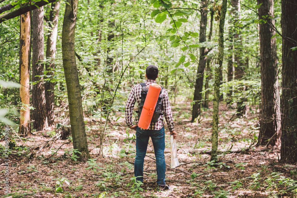 Man with Backpack and map searching directions in wilderness area. Tourist with backpack using map in forest. concept tourism holidays. Hiking man. Traveling man lost walking in forest looking at map
