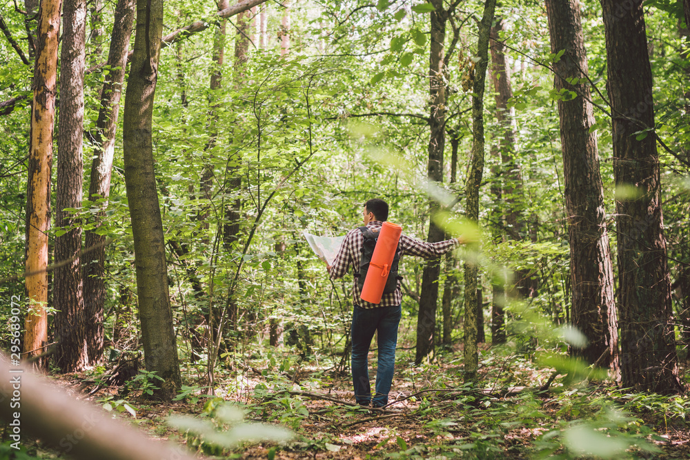 Man with Backpack and map searching directions in wilderness area. Tourist with backpack using map in forest. concept tourism holidays. Hiking man. Traveling man lost walking in forest looking at map Man with Backpack and map searching directions in wilderness area. Tourist with backpack using map in forest. concept tourism holidays. Hiking man. Traveling man lost walking in forest looking at map