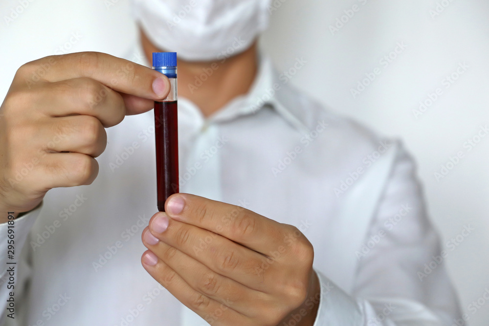 Test tube in male hands close up, man in medical mask holding a vial with red liquid. Concept of blood sample, medical and chemical research, vaccination, doctor or scientist Test tube in male hands close up, man in medical mask holding a vial with red liquid. Concept of blood sample, medical and chemical research, vaccination, doctor or scientist