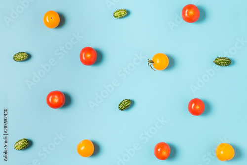 Colorful food pattern of mini cucumbers and yellow and red tomatoes on blue background. flat lay