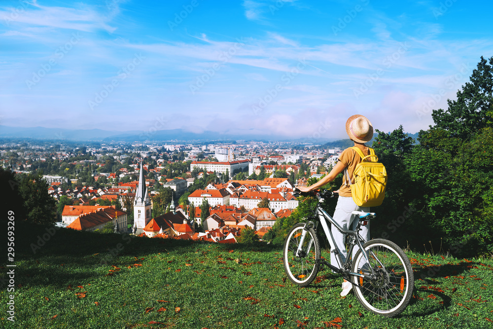 Obraz na płótnie Girl with backpack and bicycle explores Ljubljana. Travel Slovenia w salonie