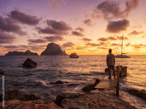 atardecer de otoño en la playa y embarcadero de Cala D´hort con vistas a Es Vedra. Hombre observando los barcos y el paisaje © Helena GARCIA