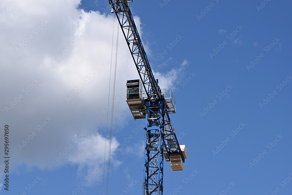 Tower crane with a cabin and an arrow on a background of the sky.