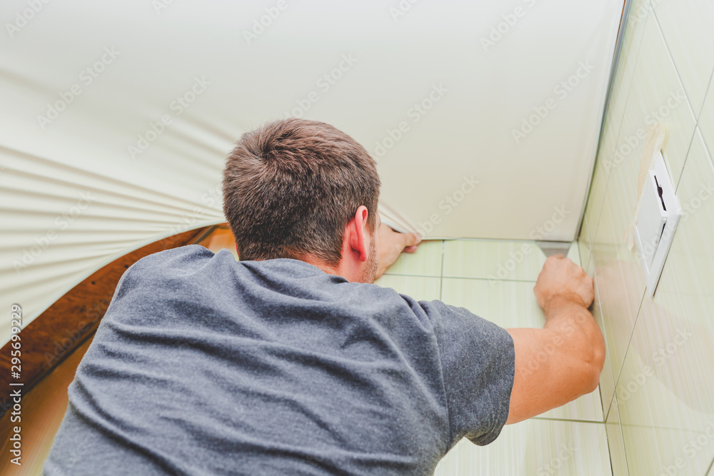 Man installing stretch ceiling in the bathroom. Man installing stretch ceiling in the bathroom.