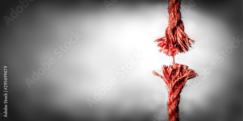 Frayed Red Rope Hanging By Last Thread On Black And White Background With Copy space photo