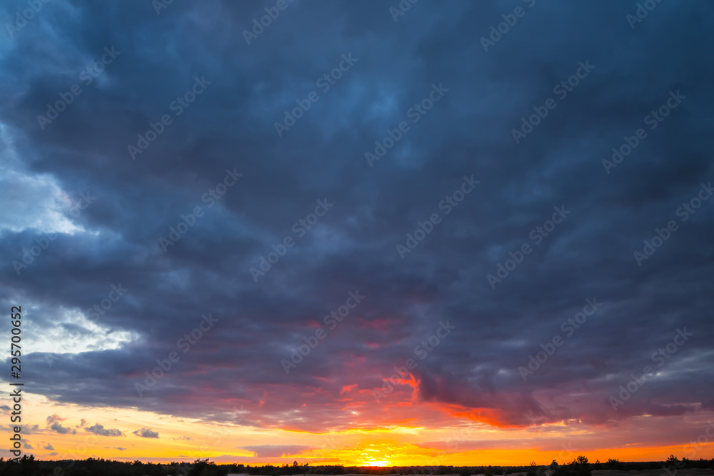 dramatic sunset over the prairies, dark dense clouds and red evening sun