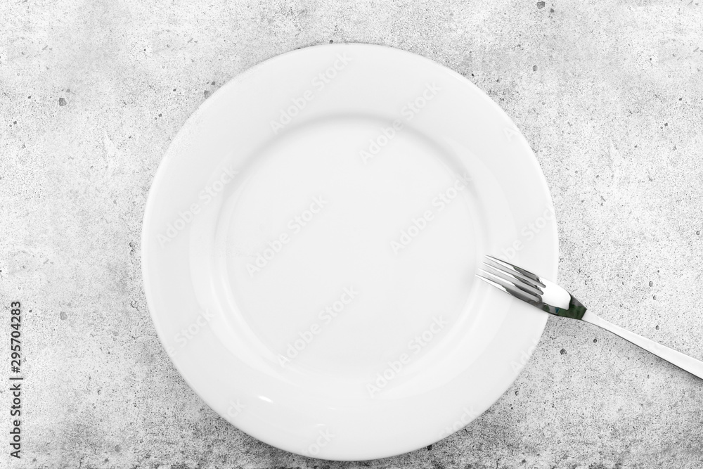 Table setting. Empty plate, fork on a light concrete background. A fork lies on a plate, a pause in food. Top view and flat lay with copy space Table setting. Empty plate, fork on a light concrete background. A fork lies on a plate, a pause in food. Top view and flat lay with copy space