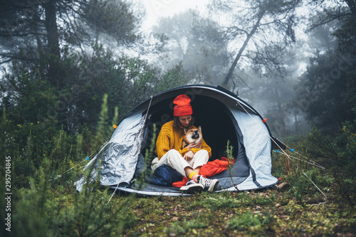 tourist traveler in camp tent hug shiba inu background foggy rain forest, smile woman with puppy dog in mist nature trip, friendship love concept, happy girl resting dog together in campsite park © A_B_C