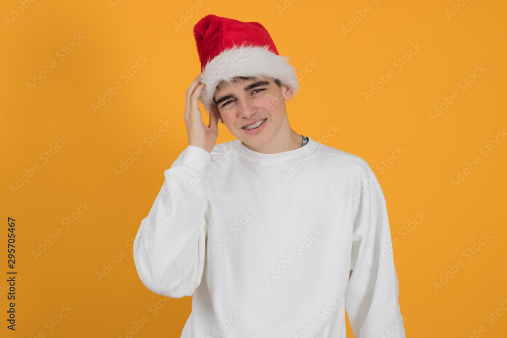 young teenage man with santa claus hat isolated on color background young teenage man with santa claus hat isolated on color background