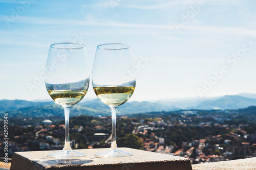Two drink glass white wine standing on background blue sea top view city coast yacht from observation deck, romantic toast with alcohol panoramic cityscape downtown, spain vacation