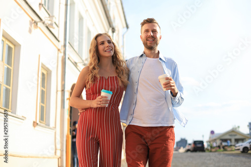 Beautiful young couple holding hands and smiling while walking through the city street