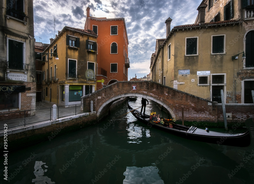 The sharp turns of the Venetian canals. A day in the life of gondoliers. Reflections in sea water. Venice. Italy.