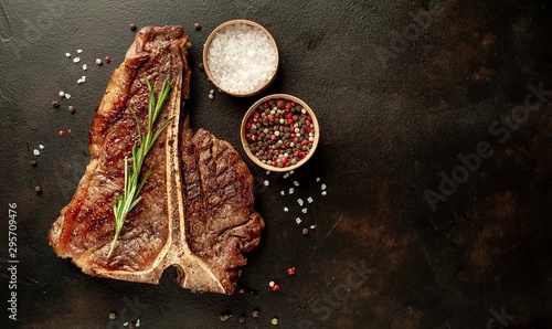 Grilled T-bone steak on a stone table. With rosemary and spices. Top view with copy space.