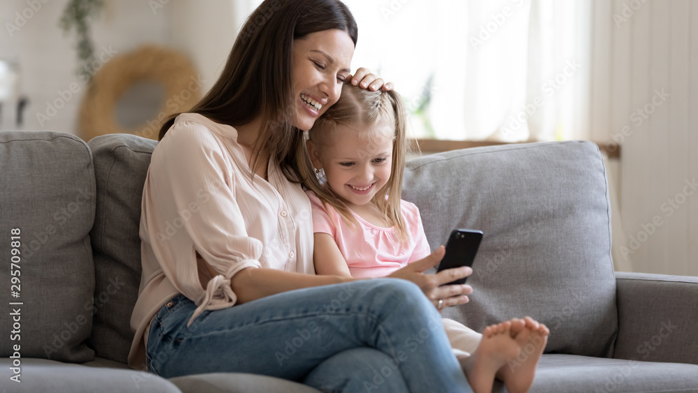 Happy mother and little daughter looking at phone screen together Happy mother and little daughter looking at phone screen together