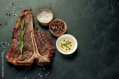 Grilled T-bone steak on a stone table. With rosemary and spices. Top view with copy space.