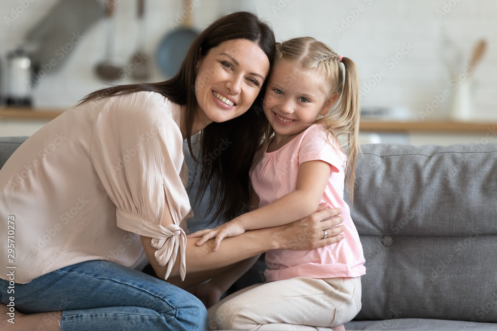 Head shot portrait smiling mother and little daughter at home