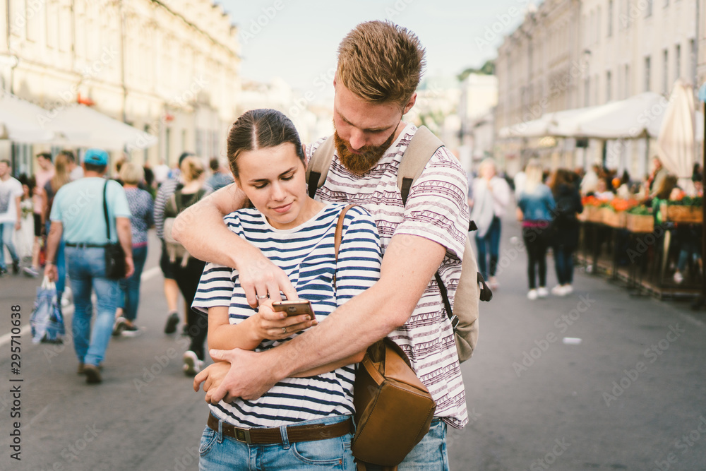 Fototapeta premium Couple tourists consulting city and mobile phone gps in street. People traveling. Couple checking location in smart phone. Technology in lifestyle. girl using navigator system app on smart phone