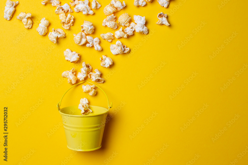 popcorn on a yellow background in a yellow bucket, he gets enough sleep from a small box, minimalism
