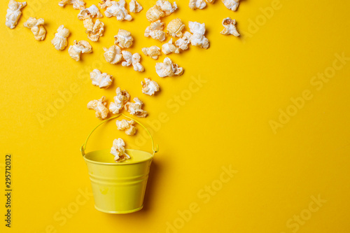 Fototapeta Naklejka Na Ścianę i Meble -  popcorn on a yellow background in a yellow bucket, he gets enough sleep from a small box, minimalism