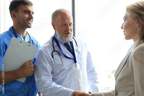 Two doctors and female patient shaking hands before consultation in the office of a modern medical center. photo