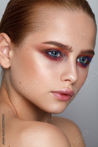 Beautiful young model with evening make up, perfect skin, sleek hairdo. Trendy colorful eye-shadows.
