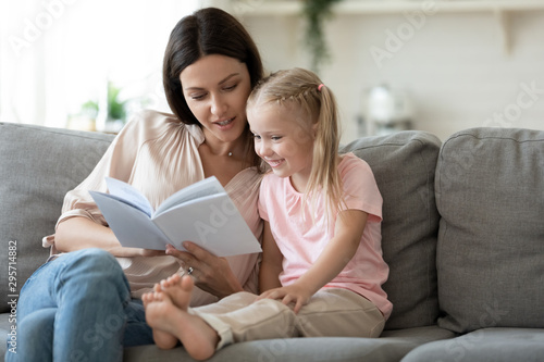 Loving mother teaching little daughter to read at home