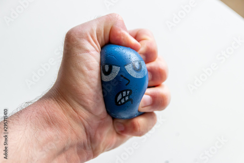 Stressabbau mit Anti-Stressball baut Stress ab durch drücken und quetschen eines blauen Balls mit bösem Gesicht und kräftig gleichzeitig Hand und Unterarmmuskulatur