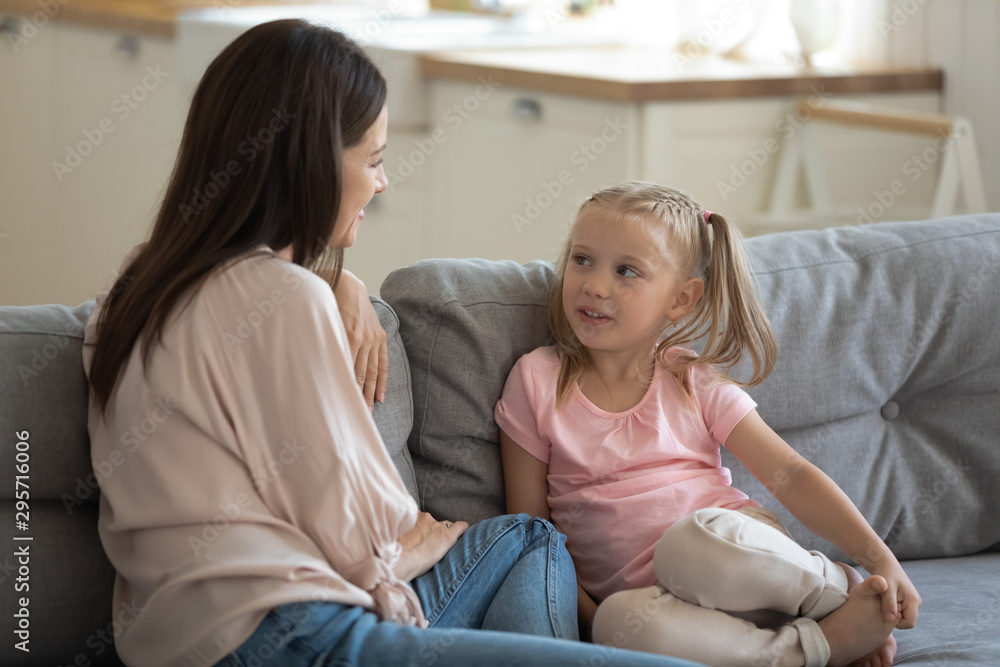 Happy mother and little daughter talking, sitting on couch Happy mother and little daughter talking, sitting on couch