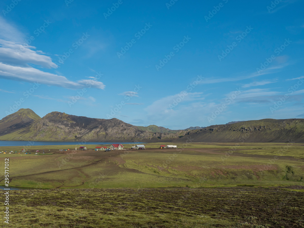 Landscape with mountain huts at camping site on blue Alftavatn lake with river, green hills and glacier in beautiful landscape of the Fjallabak Nature Reserve in the Highlands of Iceland part of