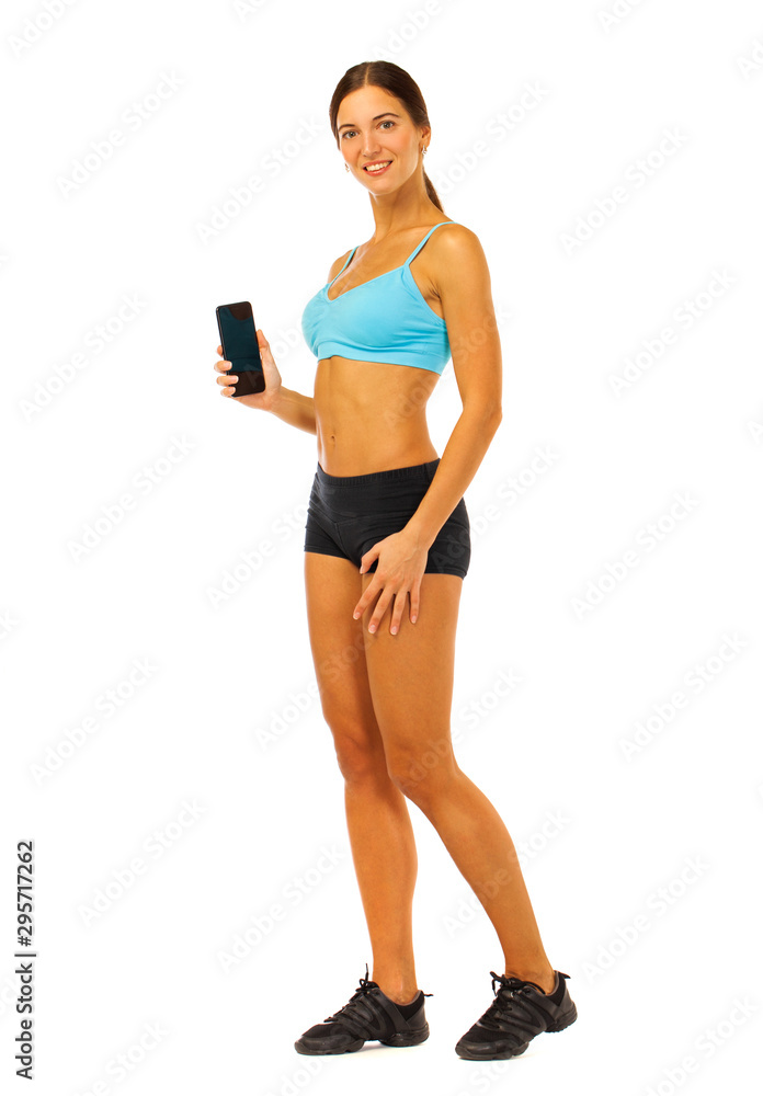 Young fitness brunette woman in blue top and black shorts posing isolated on white background Young fitness brunette woman in blue top and black shorts posing isolated on white background
