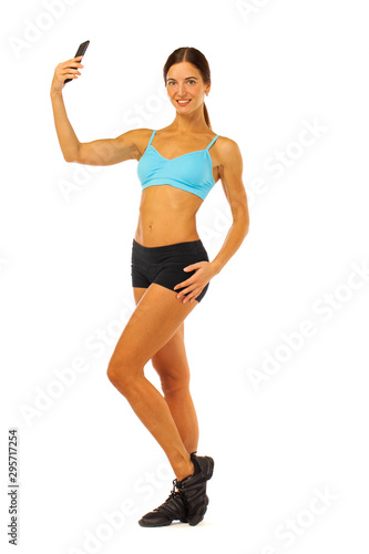 Young fitness brunette woman in blue top and black shorts posing isolated on white background