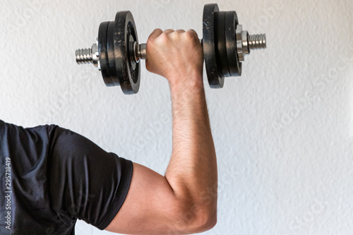 Sportler mit muskulöser Schulter und muskulösem Arm hält Kurzhantel in der rechten Hand für Fitness, Training, Bodybuilding und Kraftsport für Gesundheit und Stärke