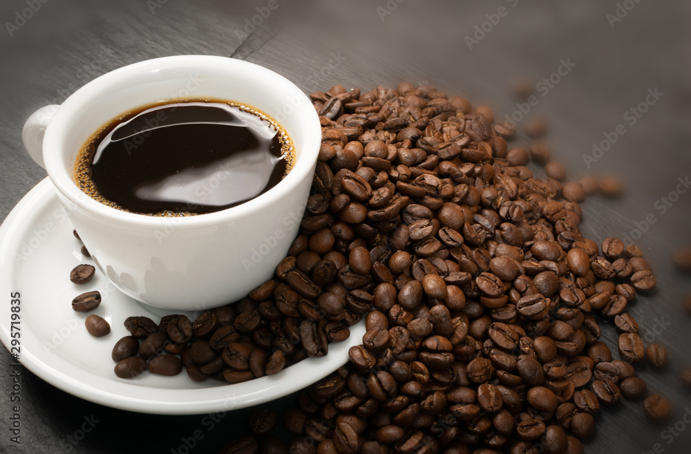 Fototapeta premium Hot coffee cup and coffee beans on black background top view