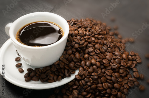 Hot coffee cup and coffee beans on black background top view